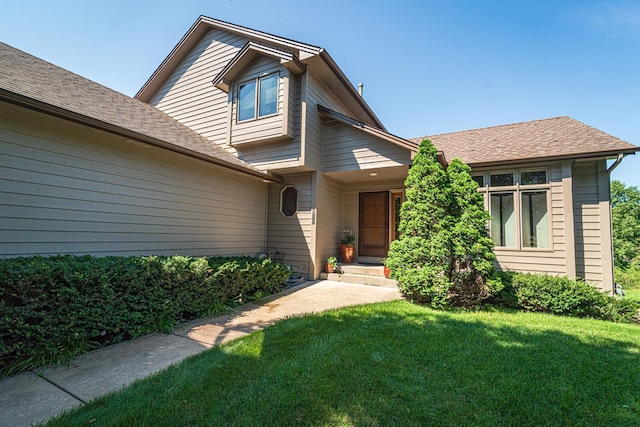 view of front of house featuring a front lawn and a shingled roof