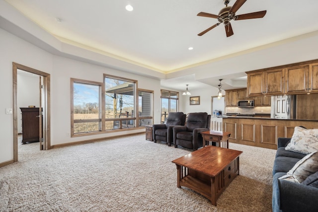 living area with baseboards, a raised ceiling, light colored carpet, ceiling fan, and recessed lighting