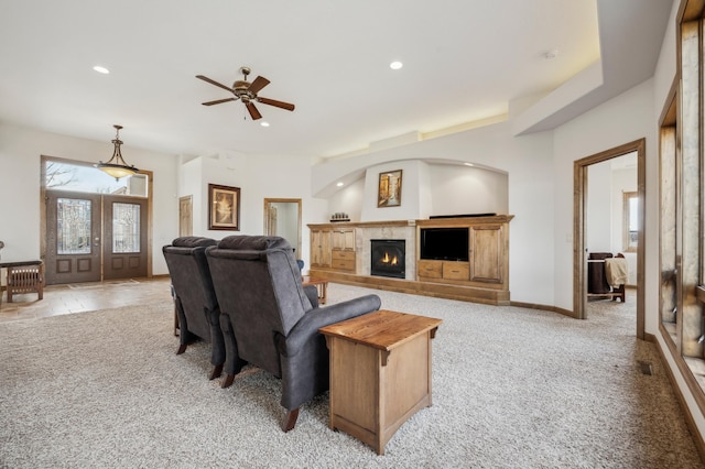 living area featuring recessed lighting, a lit fireplace, light colored carpet, and french doors