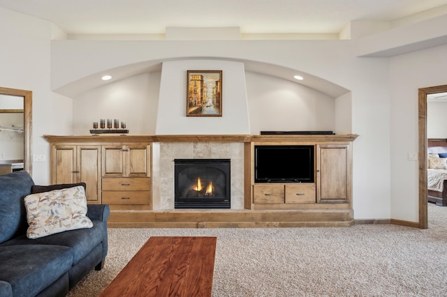 carpeted living room with a tiled fireplace and baseboards