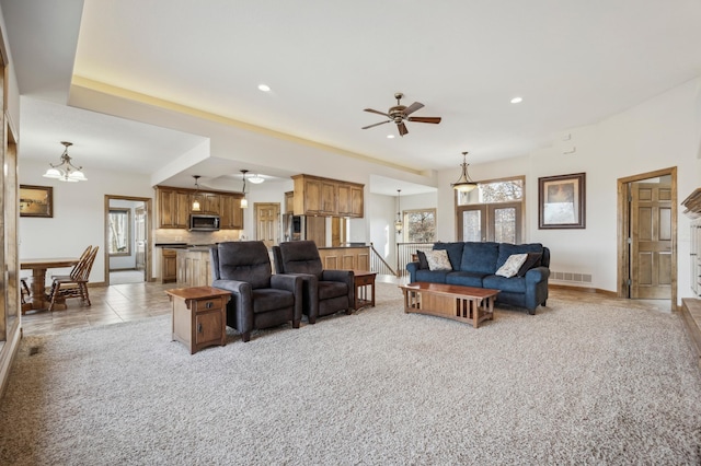 living room with ceiling fan with notable chandelier, light tile patterned floors, visible vents, and a wealth of natural light