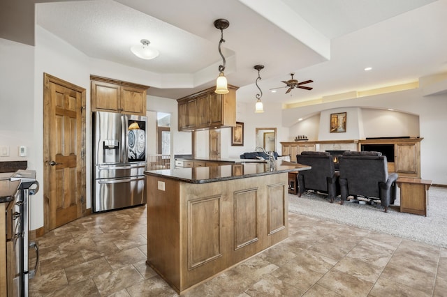 kitchen featuring open floor plan, appliances with stainless steel finishes, brown cabinetry, a raised ceiling, and pendant lighting