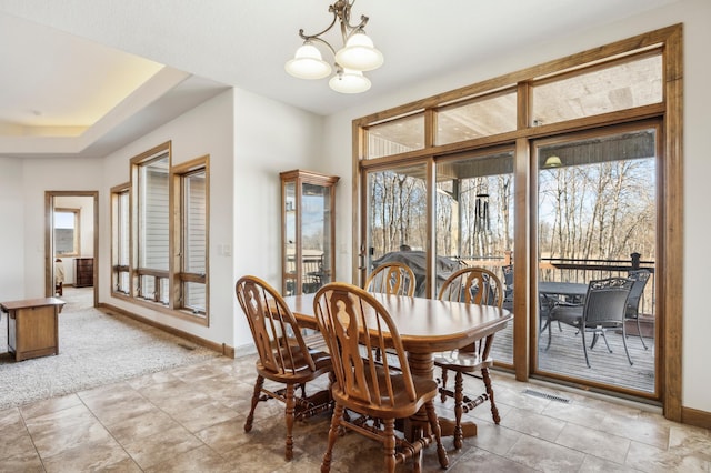 dining space with a chandelier, light colored carpet, visible vents, and baseboards