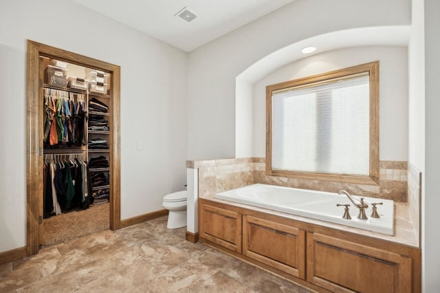 bathroom featuring a garden tub, visible vents, a spacious closet, toilet, and baseboards