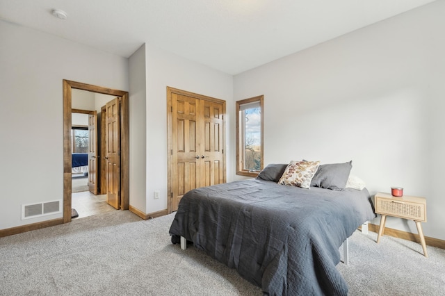 carpeted bedroom featuring a closet, visible vents, baseboards, and multiple windows