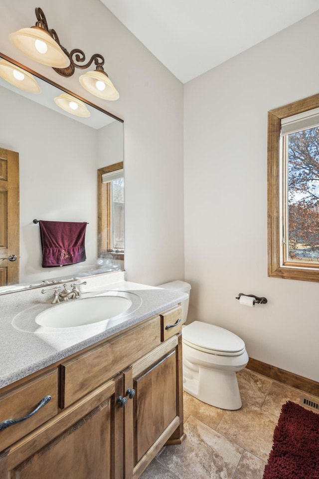 bathroom featuring toilet, visible vents, baseboards, and vanity