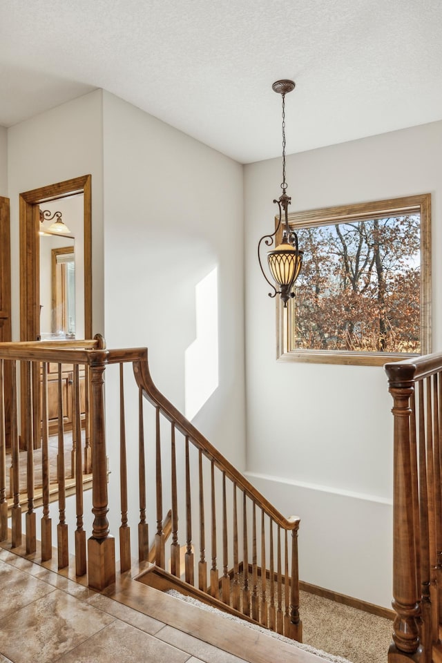 stairway featuring baseboards and a textured ceiling