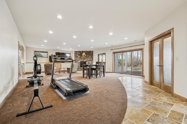 workout area featuring baseboards, visible vents, stone tile flooring, a stone fireplace, and recessed lighting