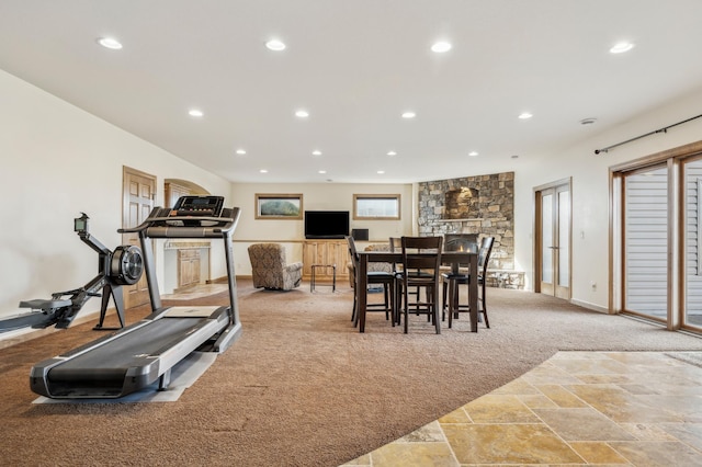 workout room featuring light carpet, stone tile floors, a stone fireplace, and recessed lighting