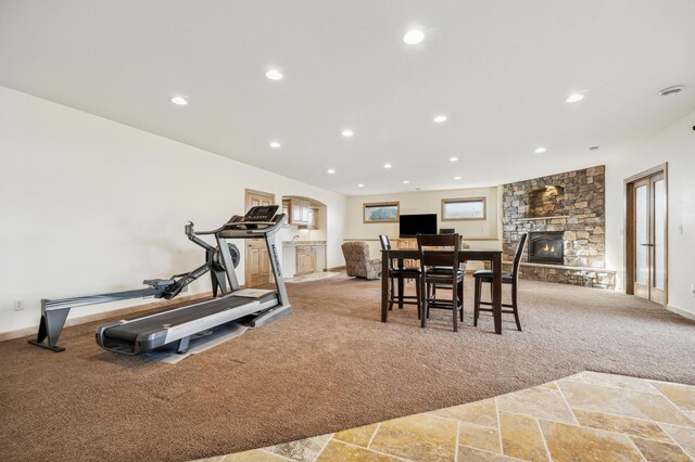 exercise area with baseboards, stone tile flooring, carpet floors, a fireplace, and recessed lighting