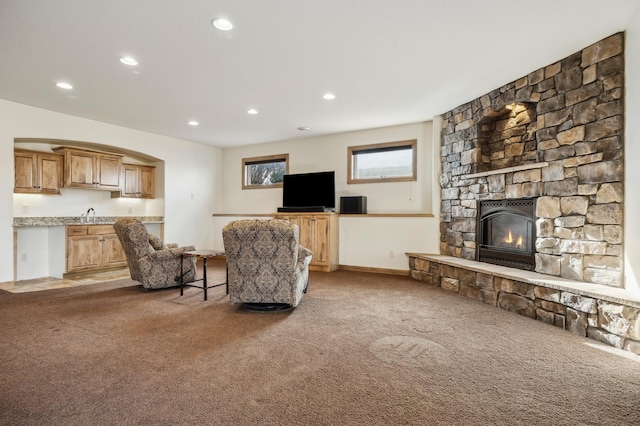 carpeted living area featuring a fireplace, a sink, and recessed lighting