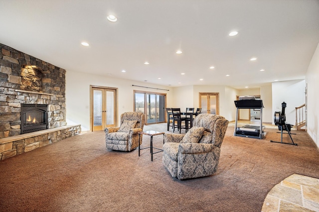 carpeted living area featuring stairway, recessed lighting, french doors, and a stone fireplace