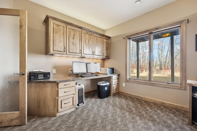 home office with baseboards, dark carpet, and built in desk