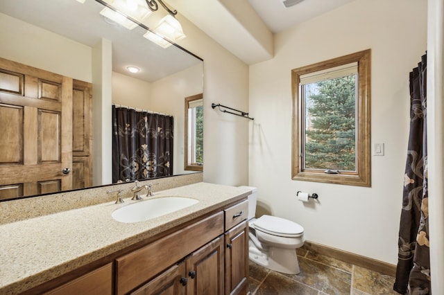 full bath with baseboards, toilet, curtained shower, stone tile flooring, and vanity