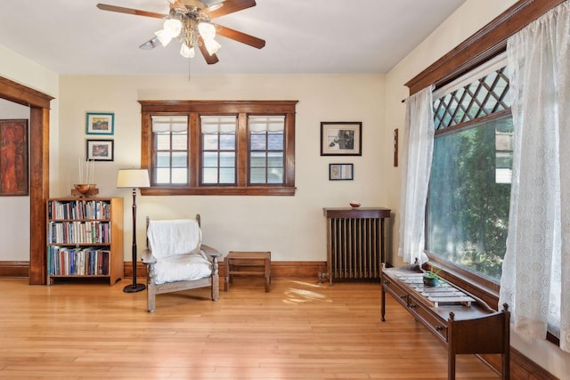 sitting room featuring a healthy amount of sunlight, radiator heating unit, baseboards, and wood finished floors