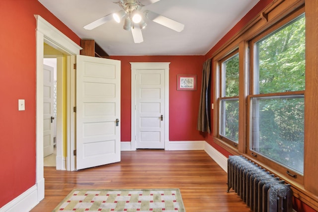 interior space with ceiling fan, radiator heating unit, wood finished floors, and baseboards