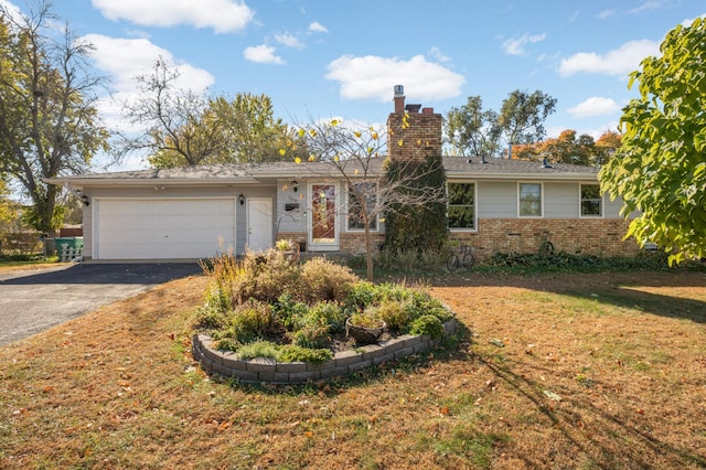 ranch-style home with brick siding, a chimney, an attached garage, a front yard, and driveway