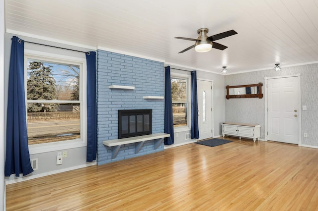 unfurnished living room featuring ornamental molding, a fireplace, ceiling fan, and wood finished floors