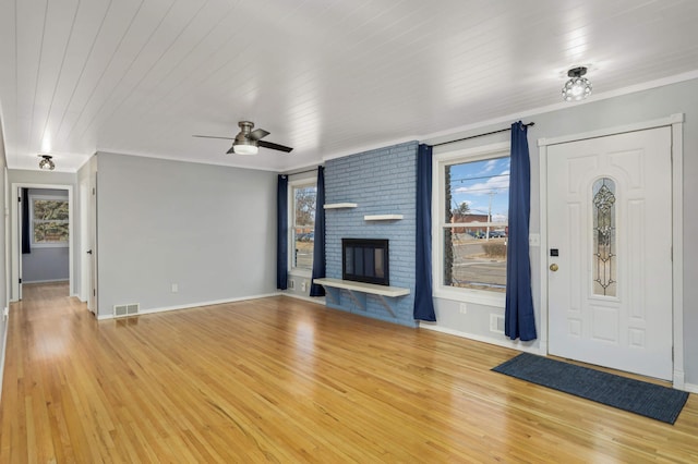 unfurnished living room featuring a healthy amount of sunlight, visible vents, a fireplace, and light wood-style flooring