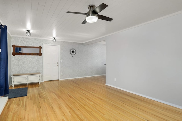 empty room with ornamental molding, wood finished floors, a ceiling fan, and baseboards