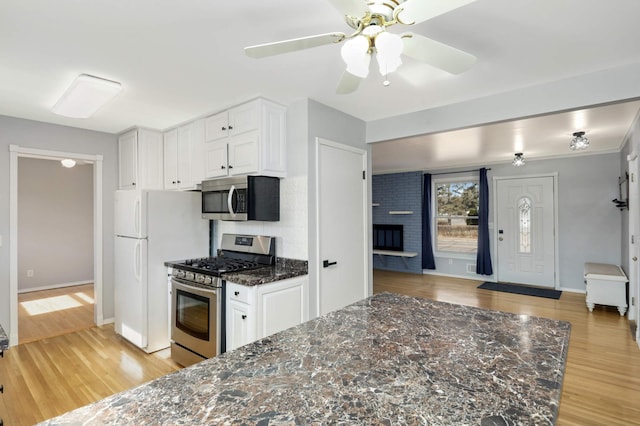 kitchen featuring light wood-style flooring, white cabinetry, stainless steel appliances, and dark stone counters