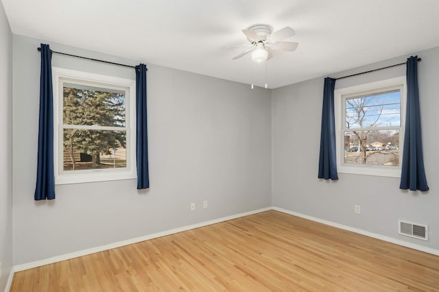 empty room with a ceiling fan, visible vents, baseboards, and wood finished floors