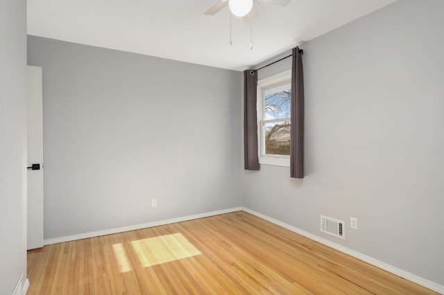 unfurnished room with a ceiling fan, visible vents, baseboards, and wood finished floors