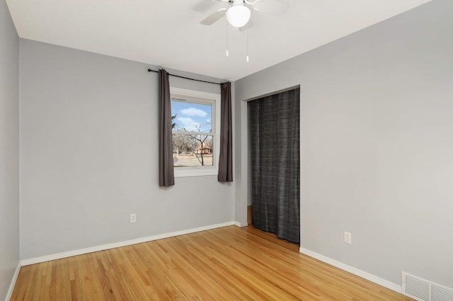 spare room featuring a ceiling fan, wood finished floors, visible vents, and baseboards