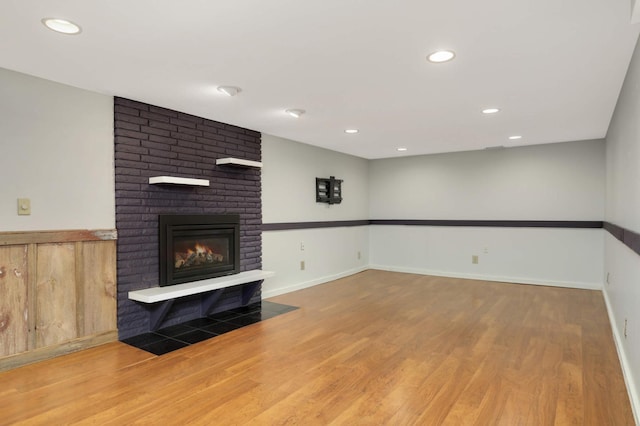 unfurnished living room featuring recessed lighting, a fireplace, wood finished floors, and baseboards