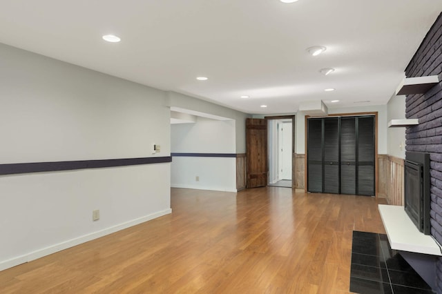 unfurnished living room with recessed lighting, a fireplace, baseboards, light wood-style floors, and wainscoting