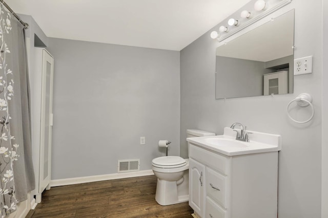 bathroom with visible vents, toilet, vanity, wood finished floors, and baseboards