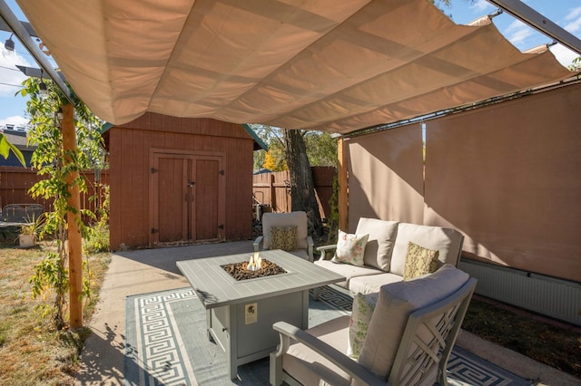 view of patio featuring an outdoor structure, fence, a shed, radiator heating unit, and an outdoor living space with a fire pit