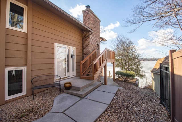 view of side of home with a chimney, stairway, fence, and brick siding