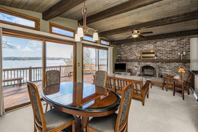 carpeted dining area featuring wooden ceiling, a brick fireplace, brick wall, and a water view