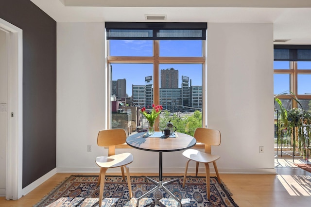 dining room featuring expansive windows, a city view, baseboards, and light wood-style floors