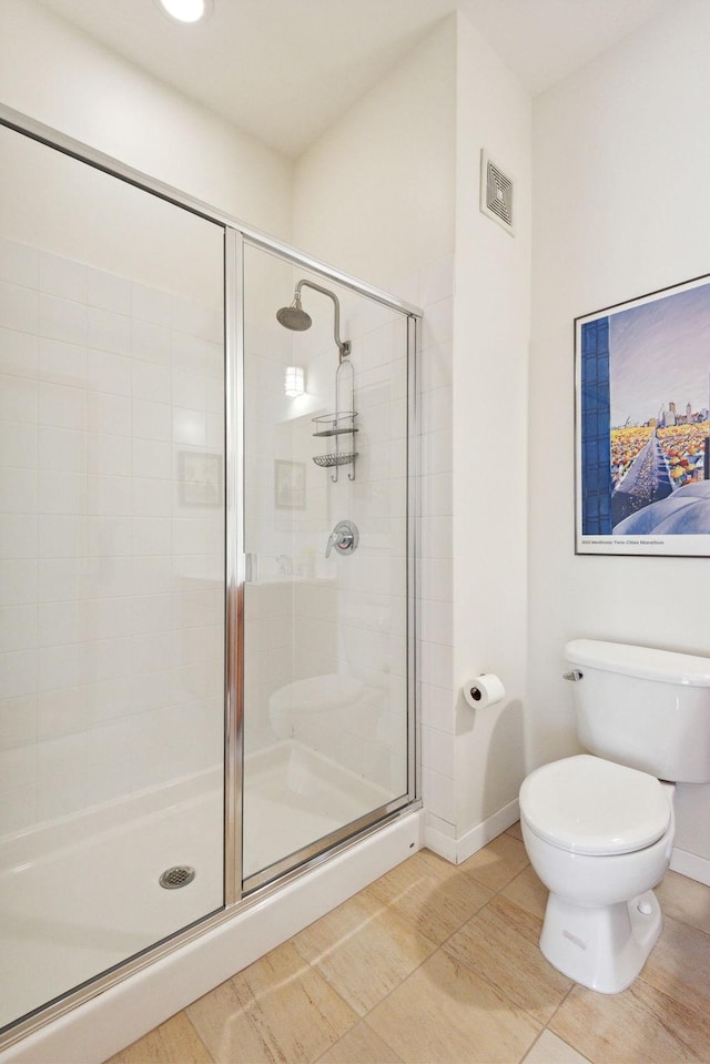 bathroom with toilet, a stall shower, baseboards, and visible vents