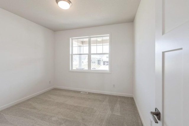 unfurnished room featuring light carpet and baseboards