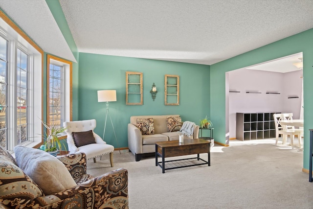 living room with a textured ceiling, carpet floors, and baseboards