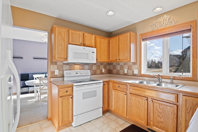 kitchen with recessed lighting, white appliances, a sink, light countertops, and tasteful backsplash