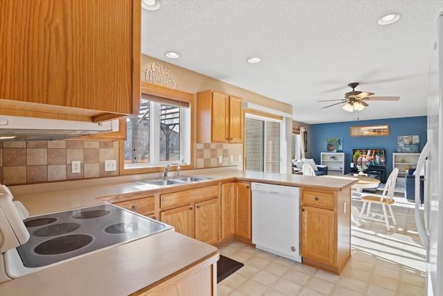 kitchen featuring light floors, white dishwasher, a peninsula, and a sink