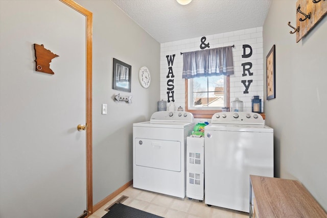 clothes washing area featuring a textured ceiling, laundry area, separate washer and dryer, baseboards, and light floors