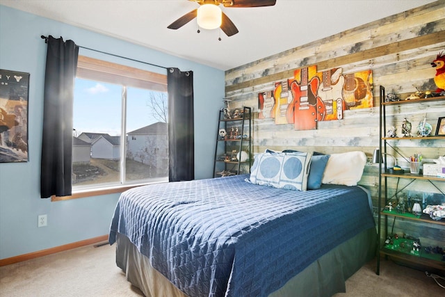 bedroom featuring ceiling fan, wooden walls, carpet floors, an accent wall, and baseboards