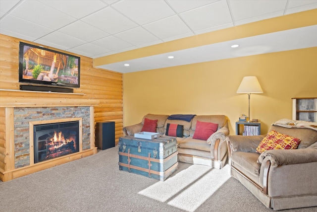 carpeted living room featuring recessed lighting, log walls, a drop ceiling, and a stone fireplace