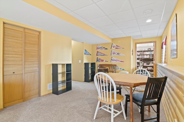 dining space featuring light carpet, visible vents, and a drop ceiling