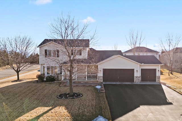 view of front of house featuring brick siding, aphalt driveway, an attached garage, a porch, and a front yard