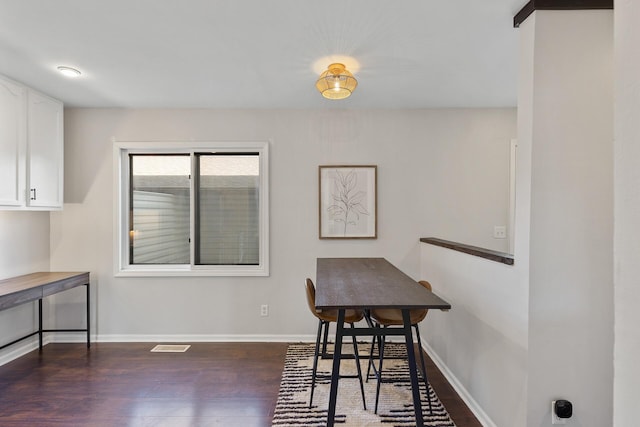 dining area with dark wood-type flooring, visible vents, and baseboards