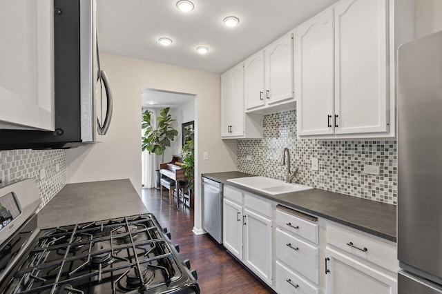 kitchen featuring dark countertops, appliances with stainless steel finishes, dark wood-style flooring, white cabinetry, and a sink