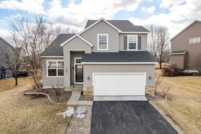 view of front of home with aphalt driveway, a front yard, roof with shingles, stone siding, and an attached garage