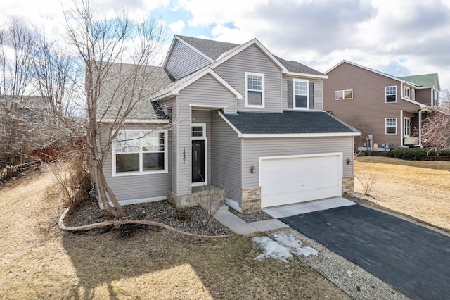 traditional-style home with aphalt driveway, an attached garage, and a shingled roof