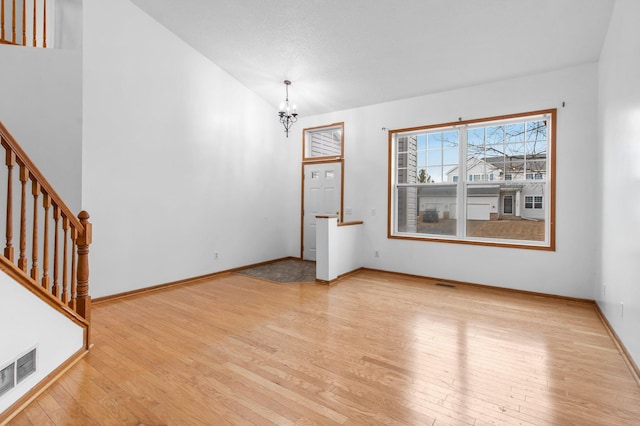 interior space featuring visible vents, a chandelier, stairway, light wood-type flooring, and lofted ceiling